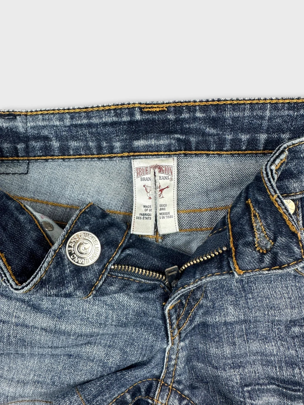Detail view of women denim shorts in dark blue with contrasting yellow stitching.