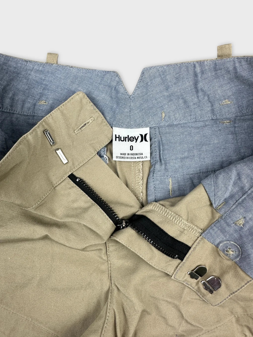 Detail view of women denim shorts featuring a beige color and black zip.