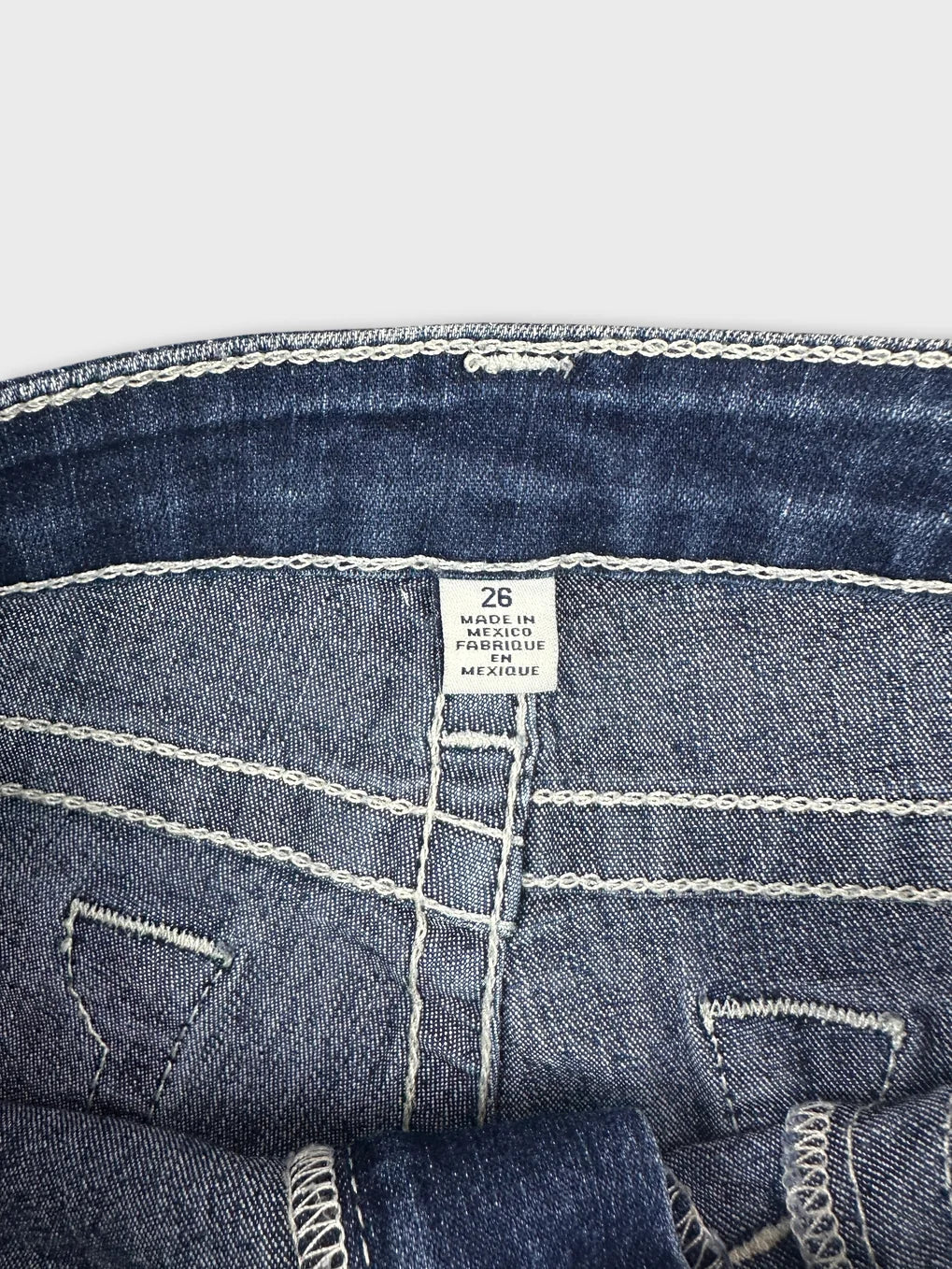 Detail view of women denim shorts showing blue color and white stitching.