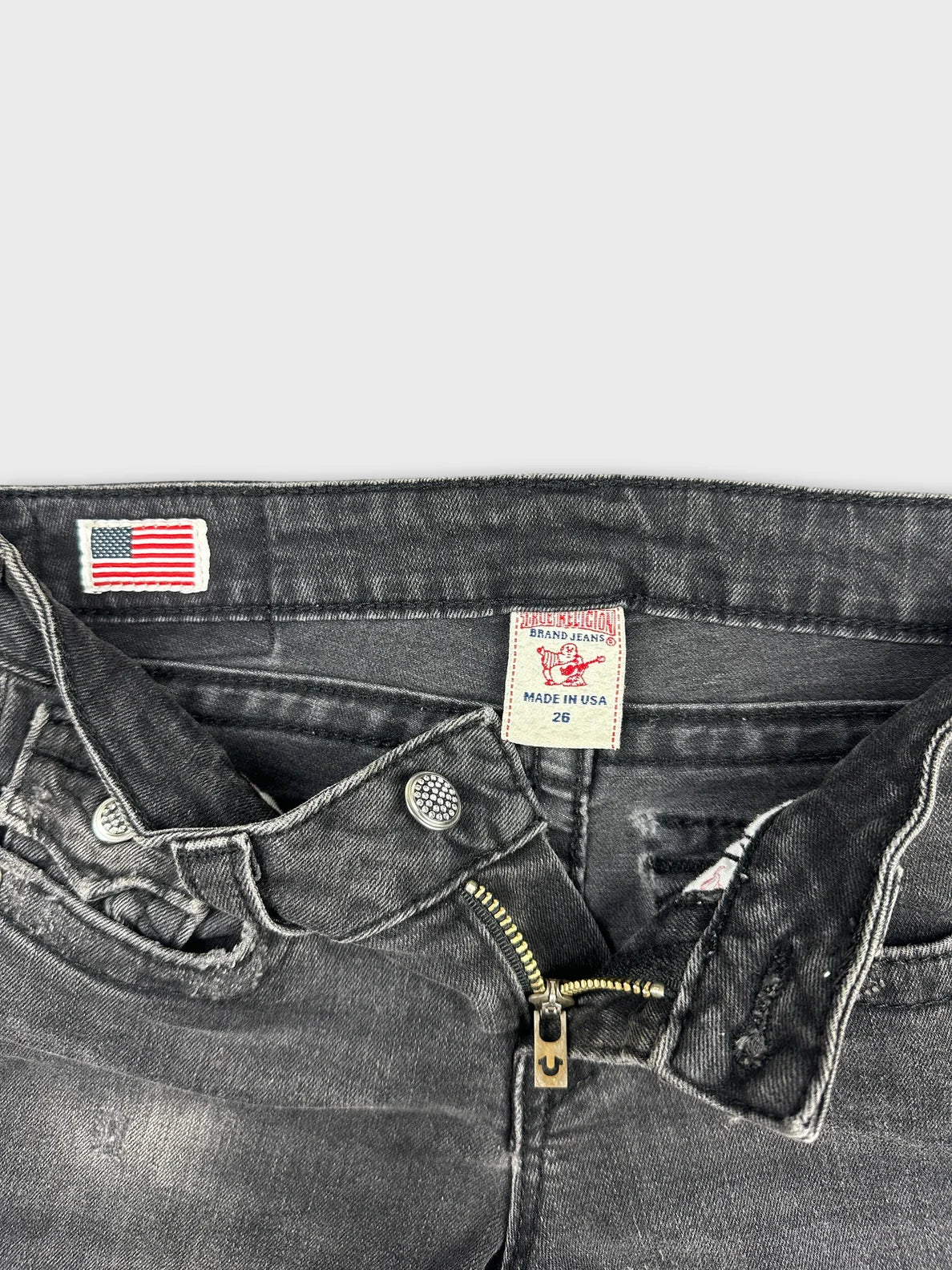 detail view of black denim shorts featuring a metal zip and button closure