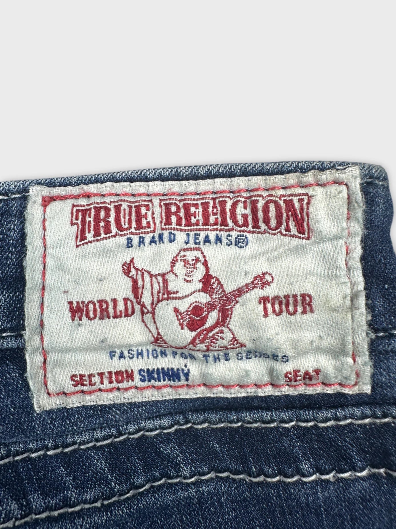Detail view of women denim shorts showing True Religion label and stitching.