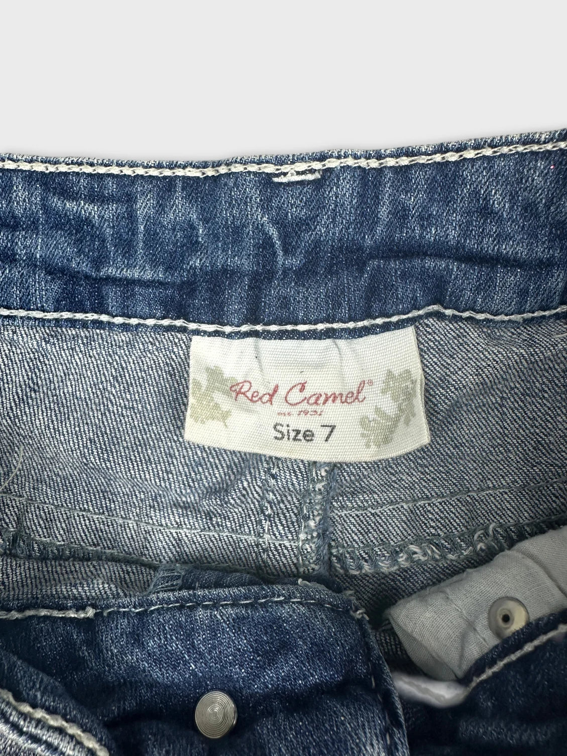 Detail view of women denim shorts in dark blue with stitching details.
