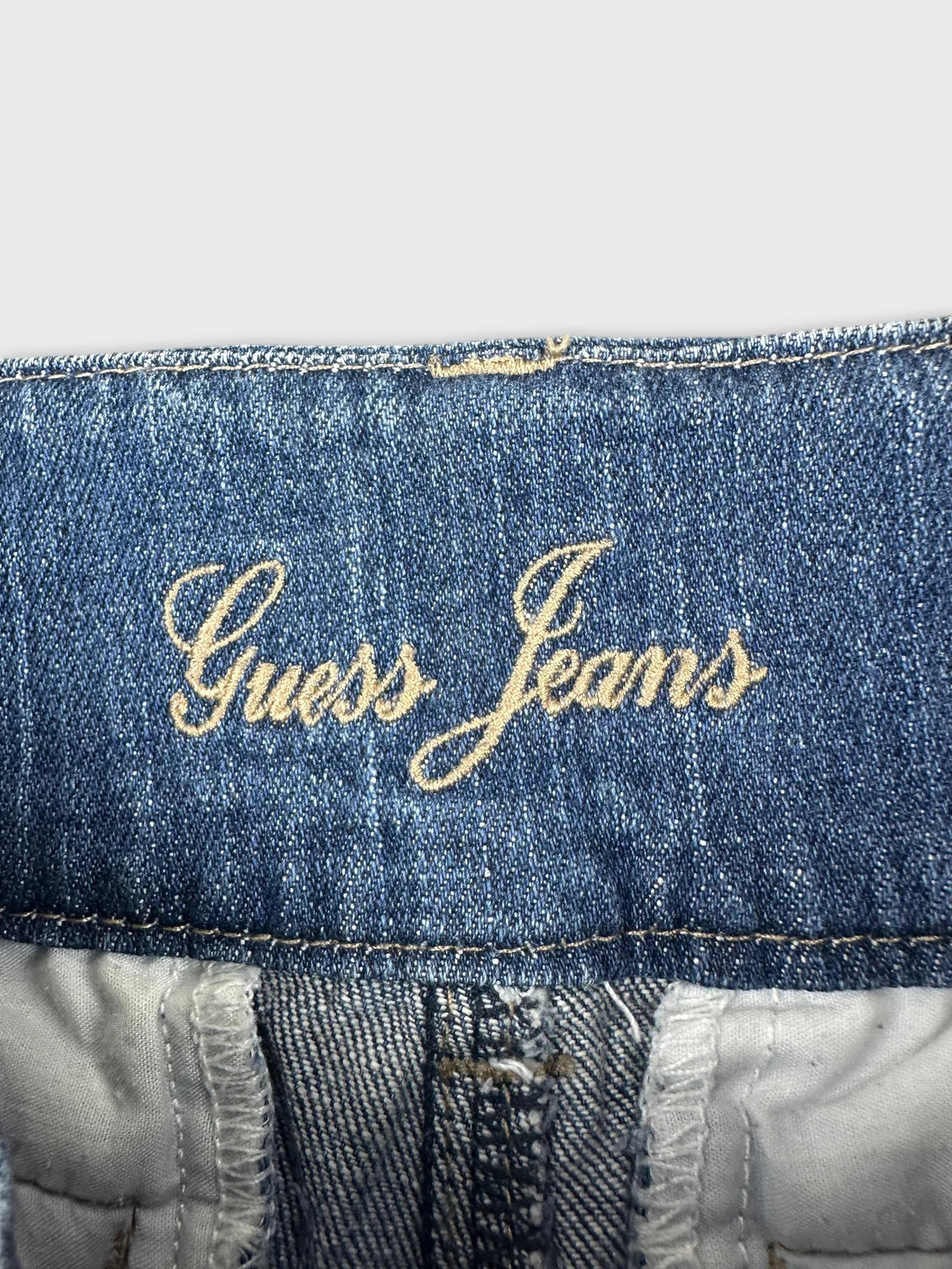 detail view of denim shorts with embroidered Guess Jeans logo