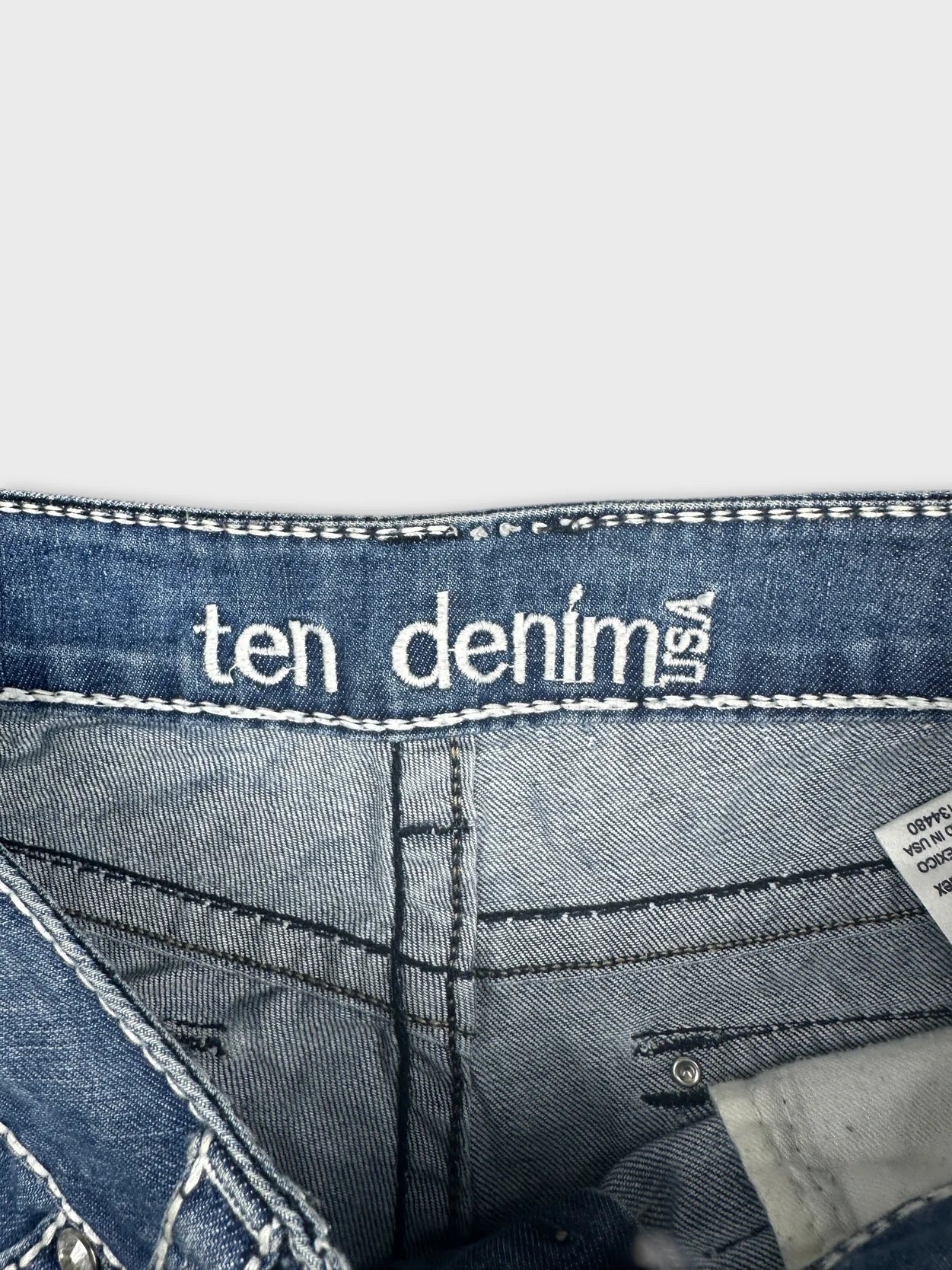 Detail view of blue denim shorts showing the interior stitching and label