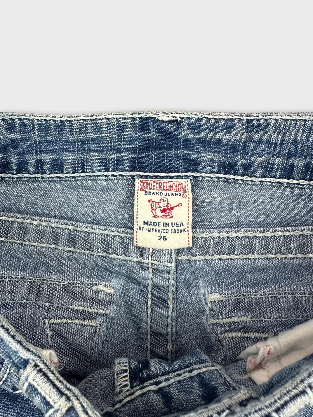 Detail view of blue denim shorts showing waistband and brand tag.