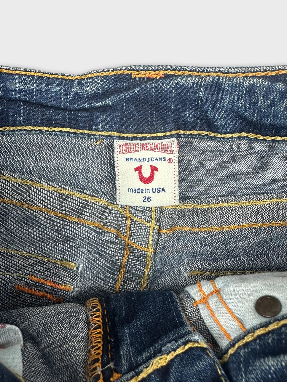 Detail view of women denim shorts in dark wash with yellow stitching.