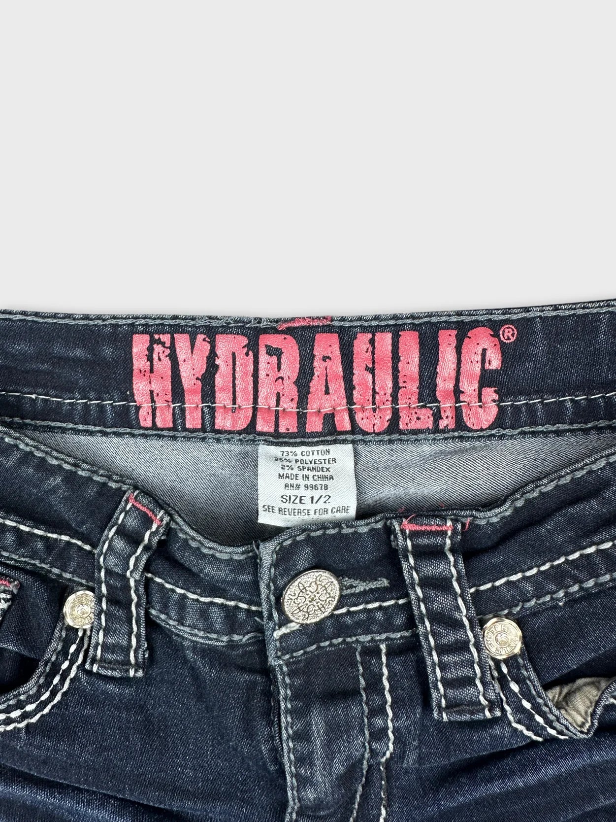 Detail view of women denim shorts featuring dark wash and decorative buttons.