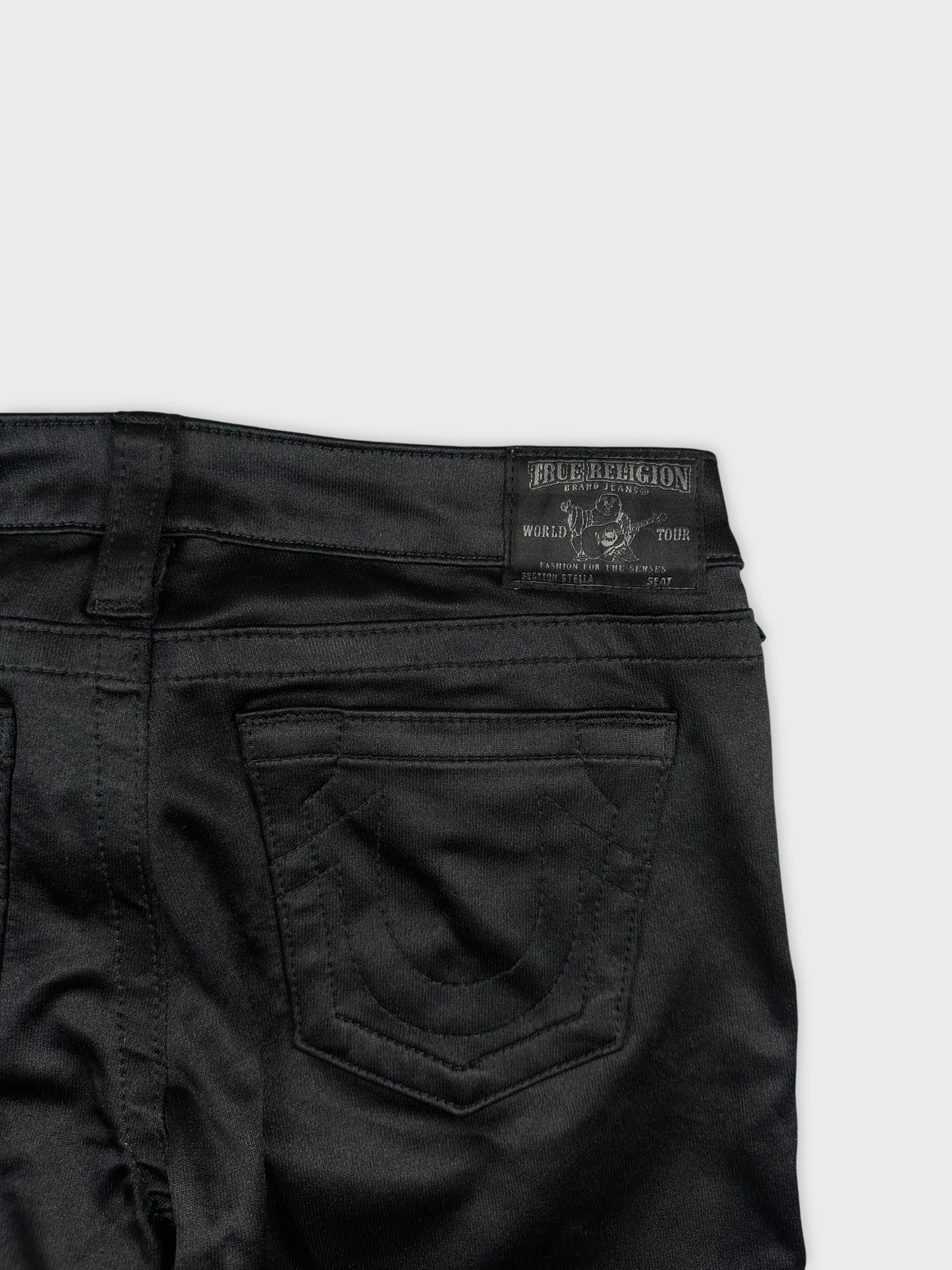 Detail view of black denim shorts featuring intricate back pocket stitching.