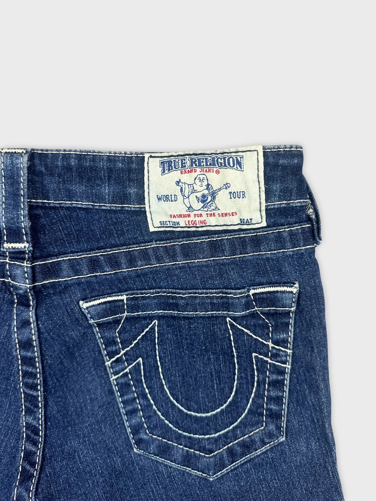 Detail view of blue denim shorts featuring an embroidered back pocket design.