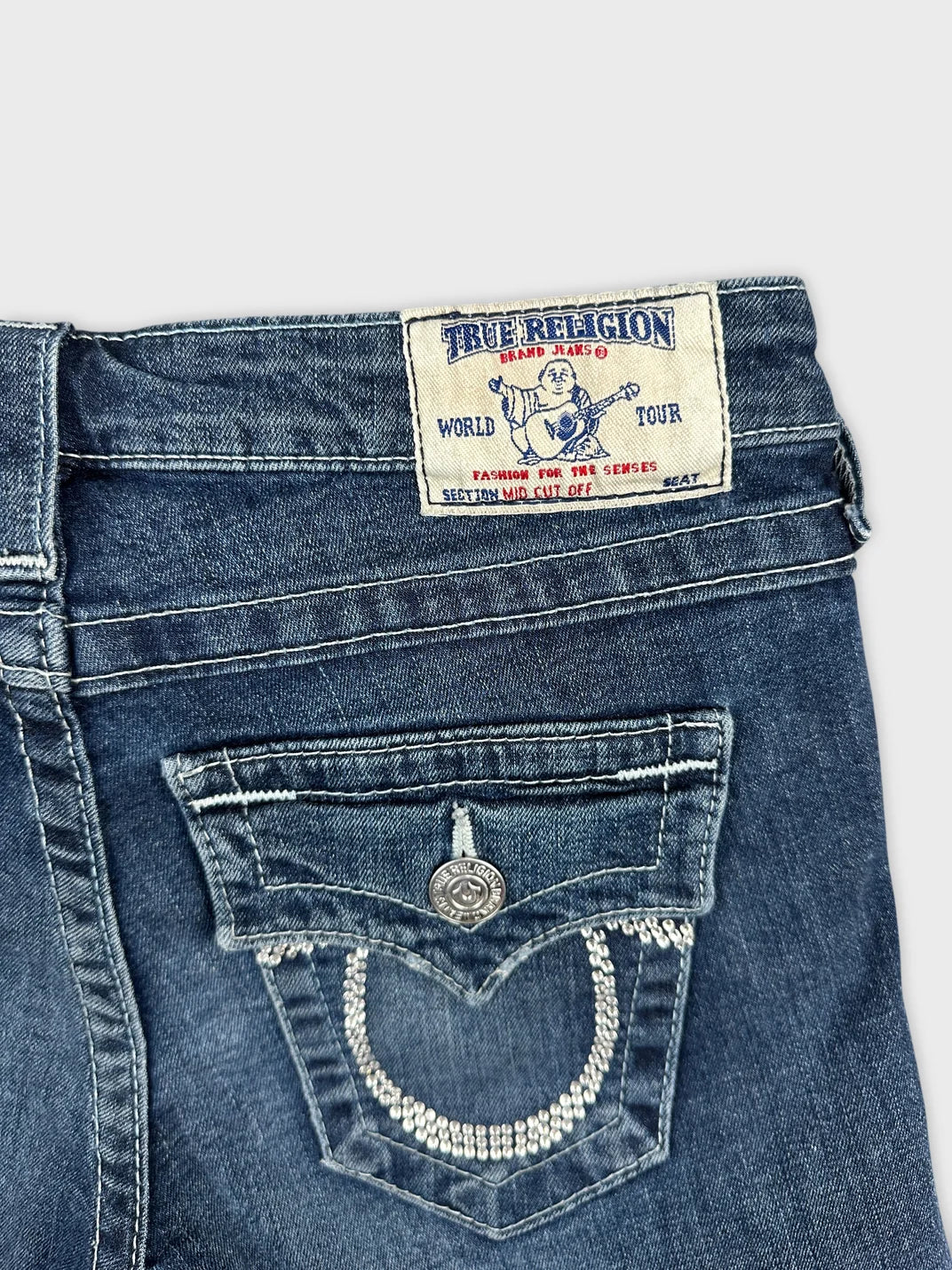Detail view of women denim shorts in dark blue with embellished back pocket.
