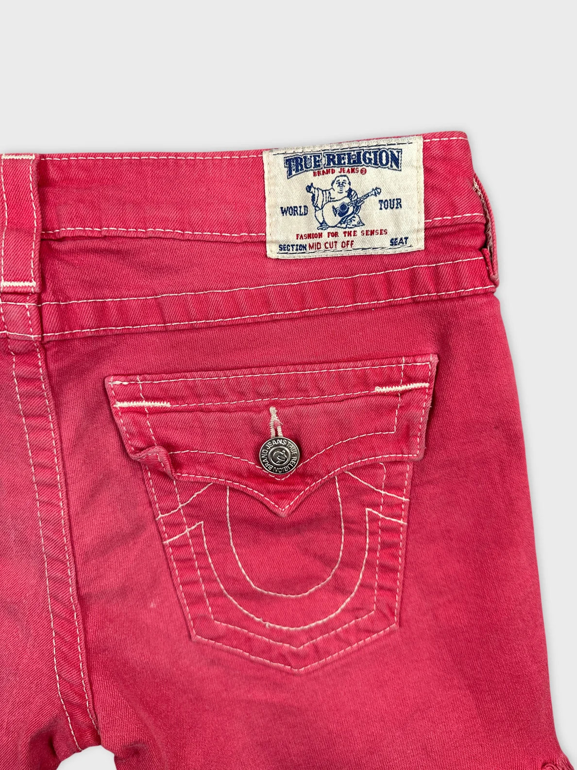 Detail view of women's denim shorts in bright pink with stitching details.
