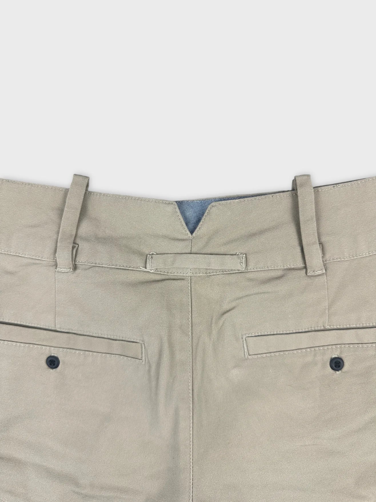 Detail view of tan denim shorts featuring back pockets and belt loops.