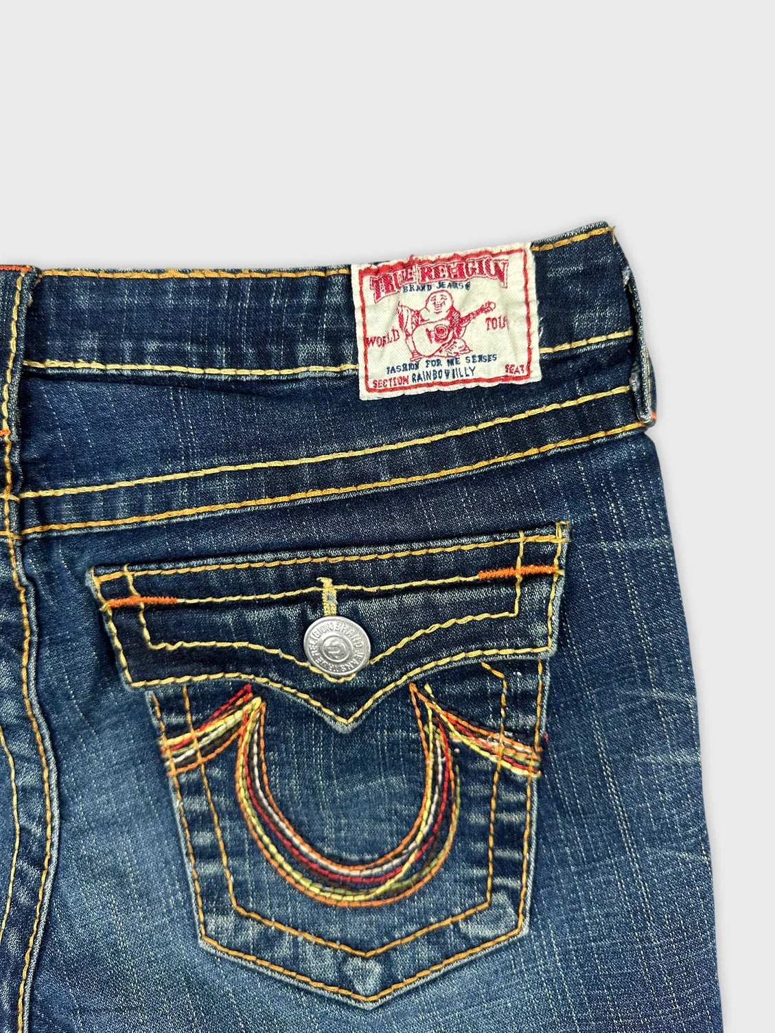 Detail view of women denim shorts featuring multicolored stitching