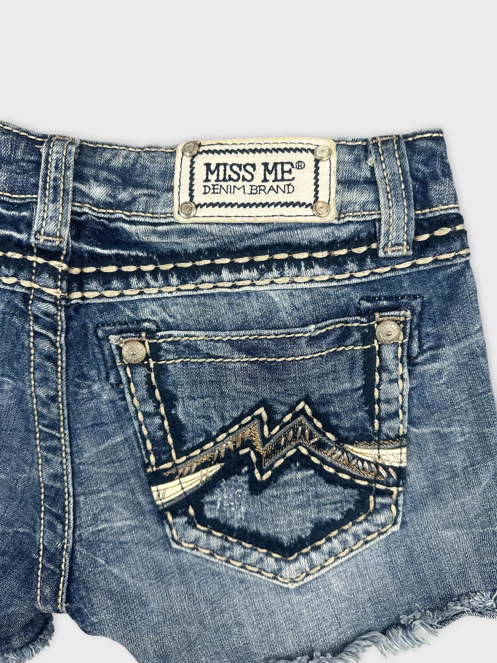 Detail view of blue denim shorts with embroidered back pocket design.