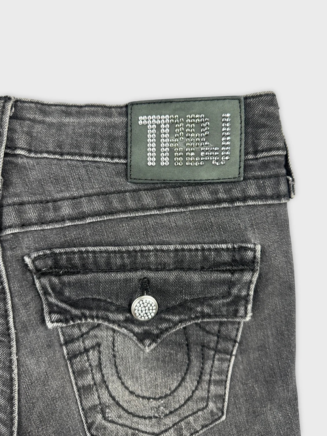 Detail view of women denim shorts in grey with a decorative back pocket.