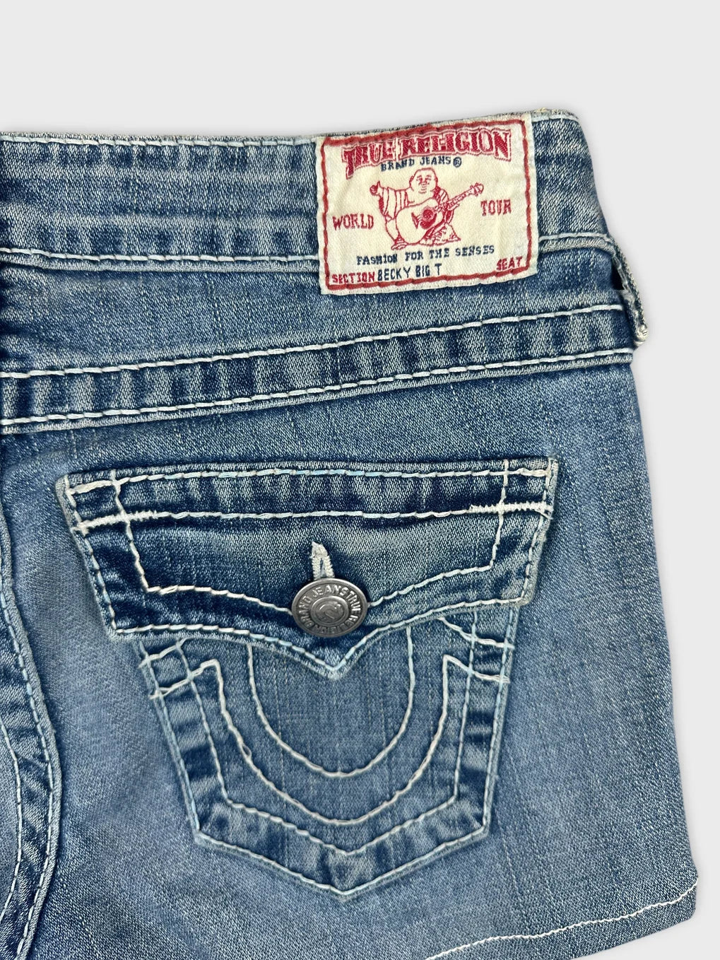Detail view of women denim shorts in light blue with embroidered back pockets.