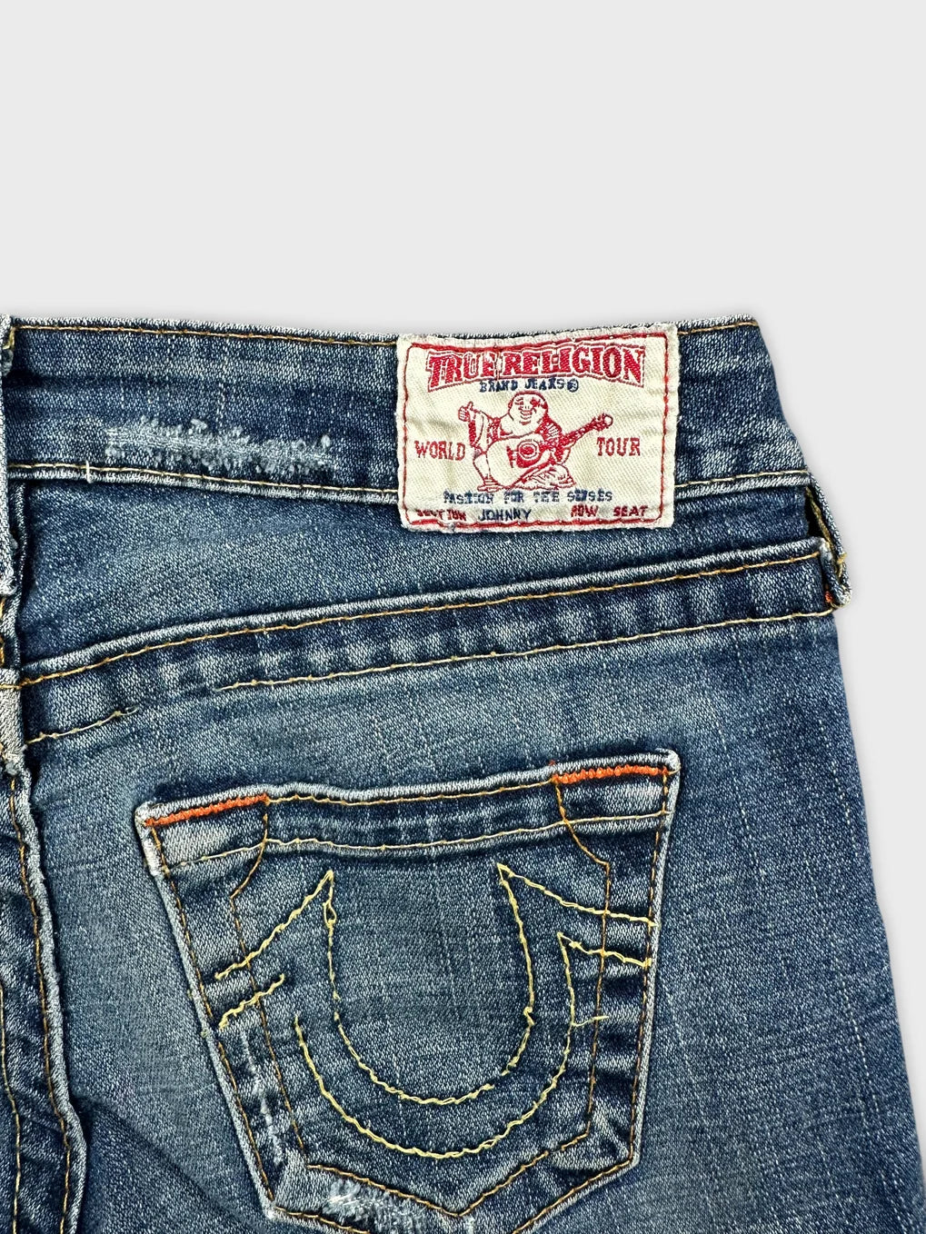 Detail view of blue denim shorts featuring embroidered back pockets.