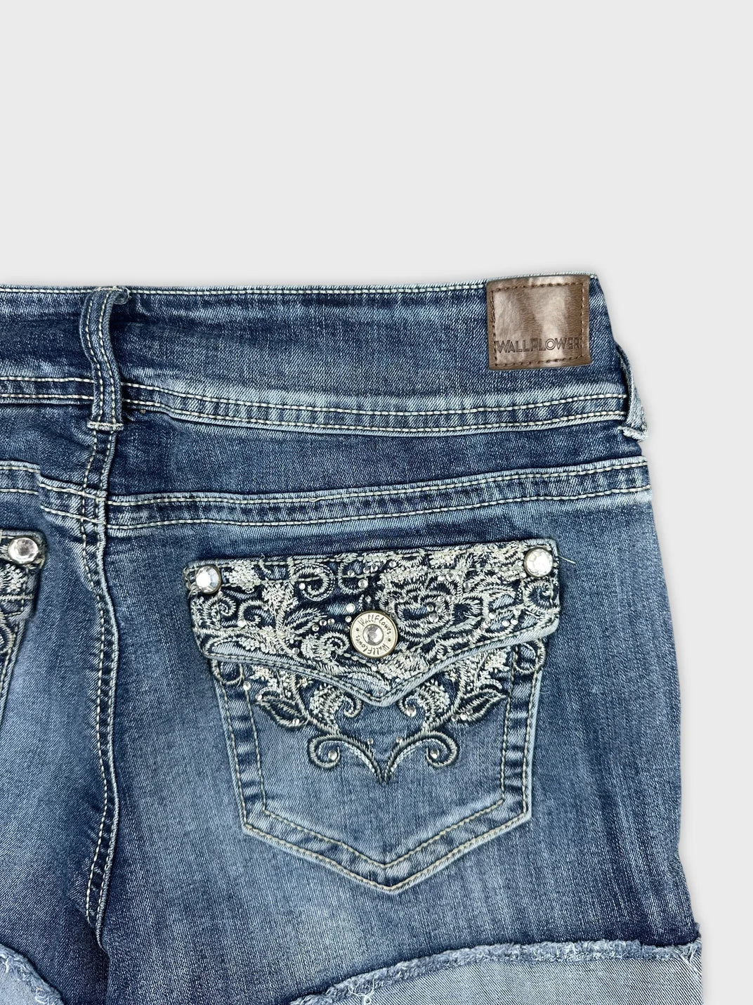 Detail view of women denim shorts in blue with embroidered back pockets.