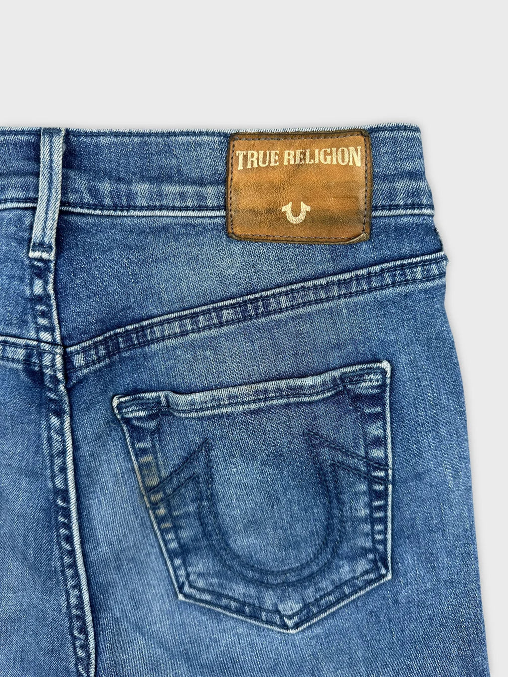 Detail view of women denim shorts in blue featuring a leather brand patch.