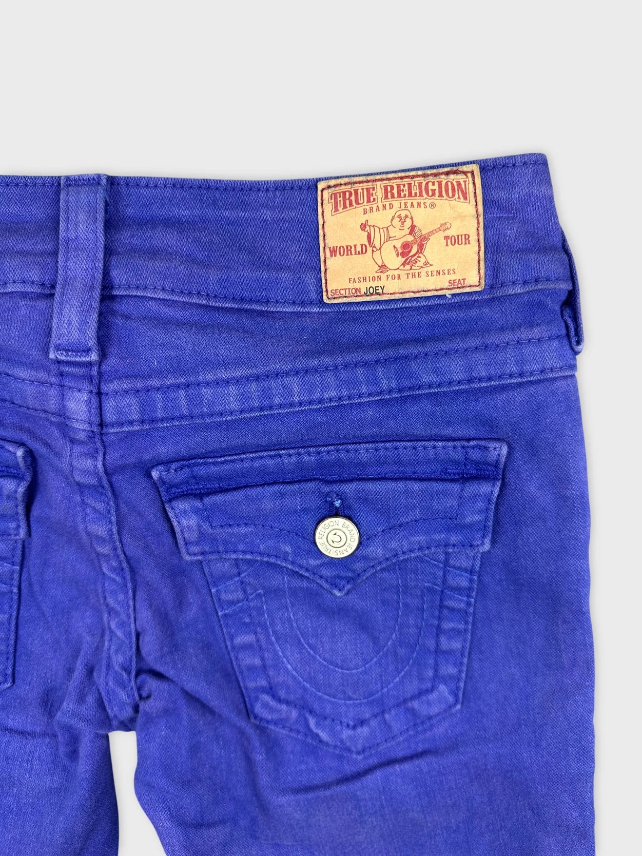 Detail view of women denim shorts in vibrant blue with logo patch.
