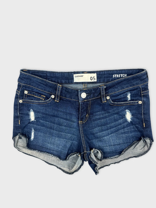 Front view of women denim shorts in dark blue with frayed hem.