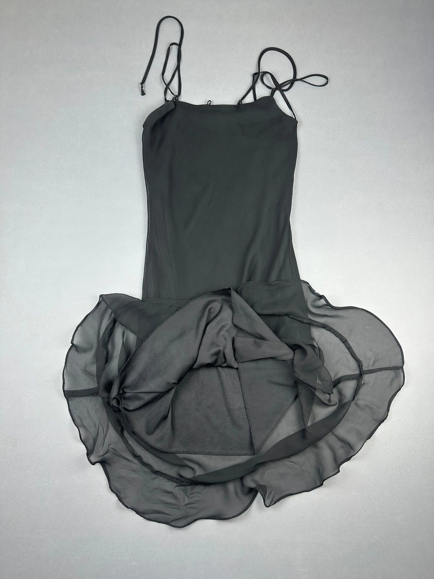 Detail view of a black long dress with ruffled overlay trim.