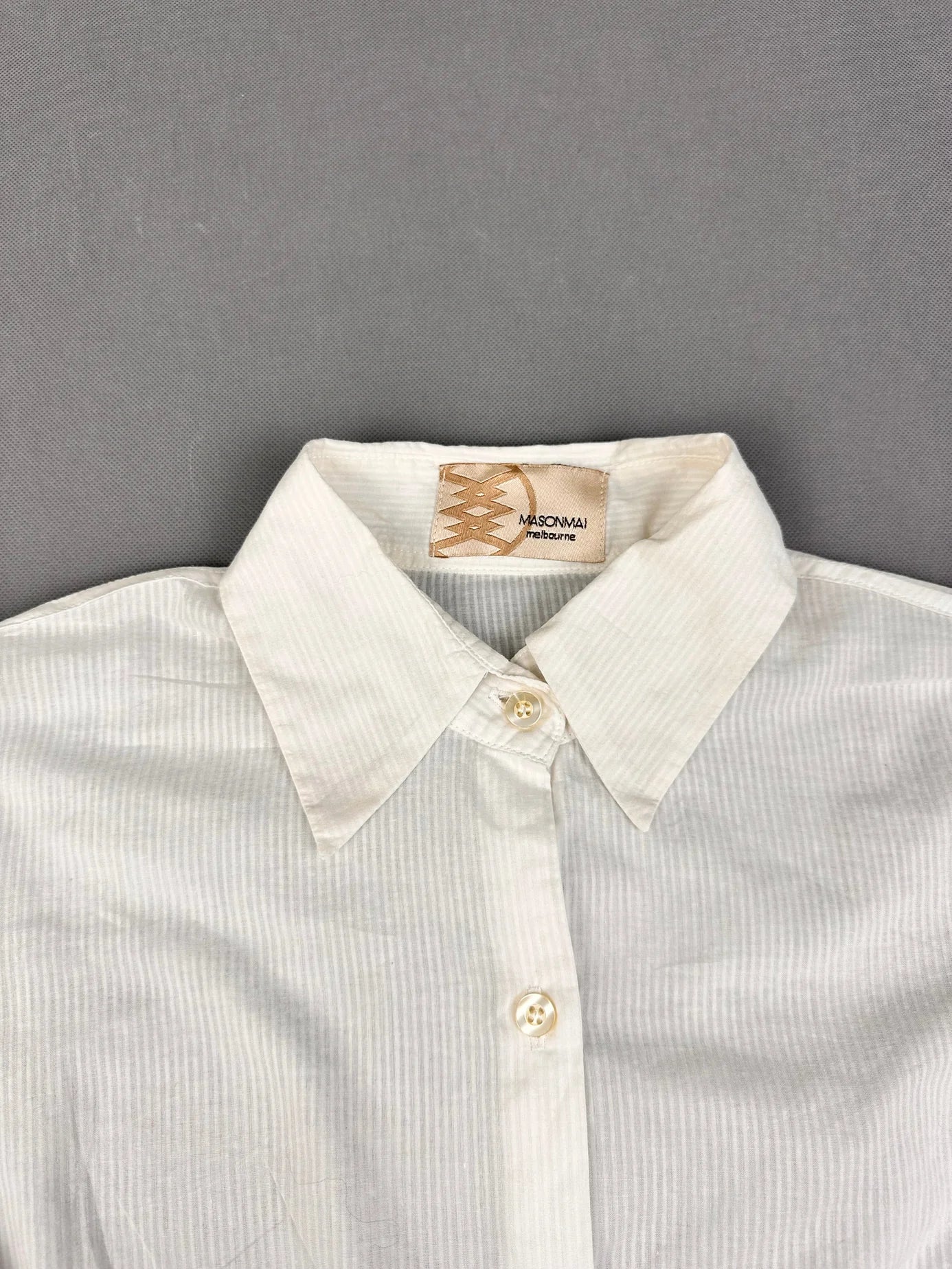 Detail view of a women long sleeve button up shirt in white with striped pattern.