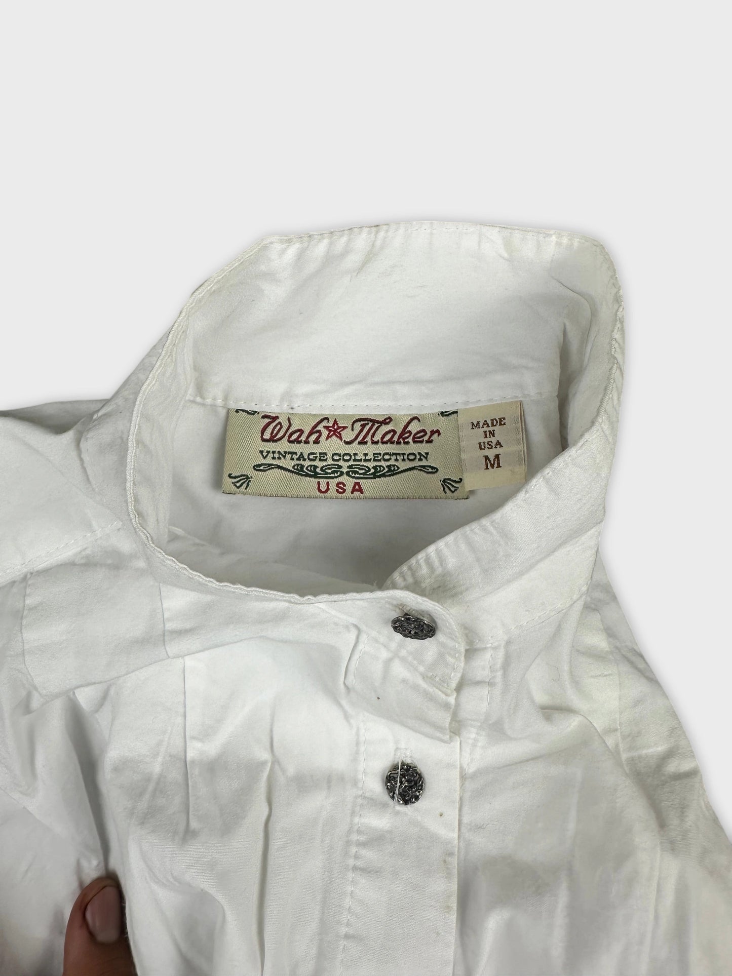 Detail view of a white long sleeve button up shirt with faint texture.
