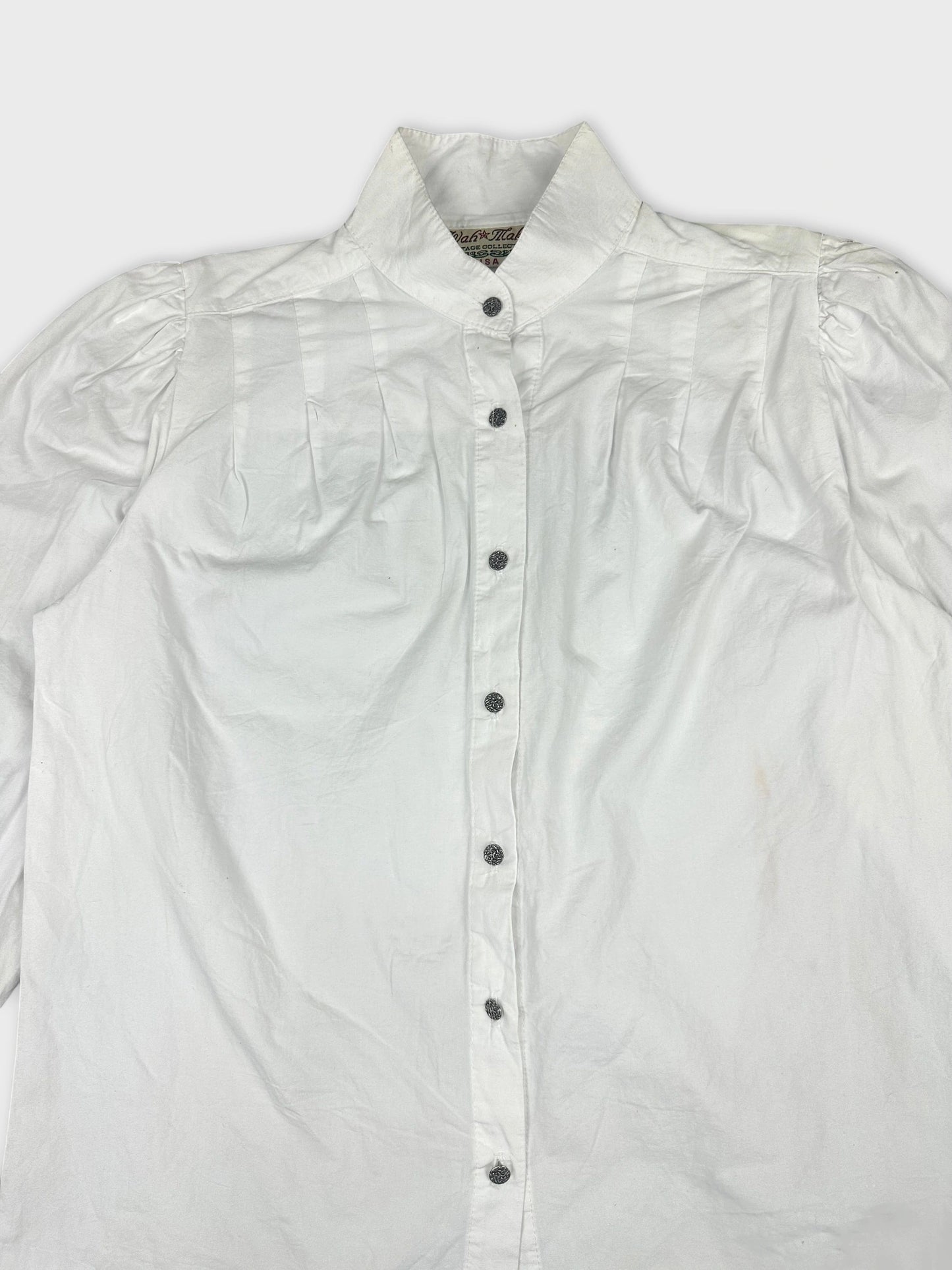 Detail view of a white long sleeve button up shirt with pleated shoulders.