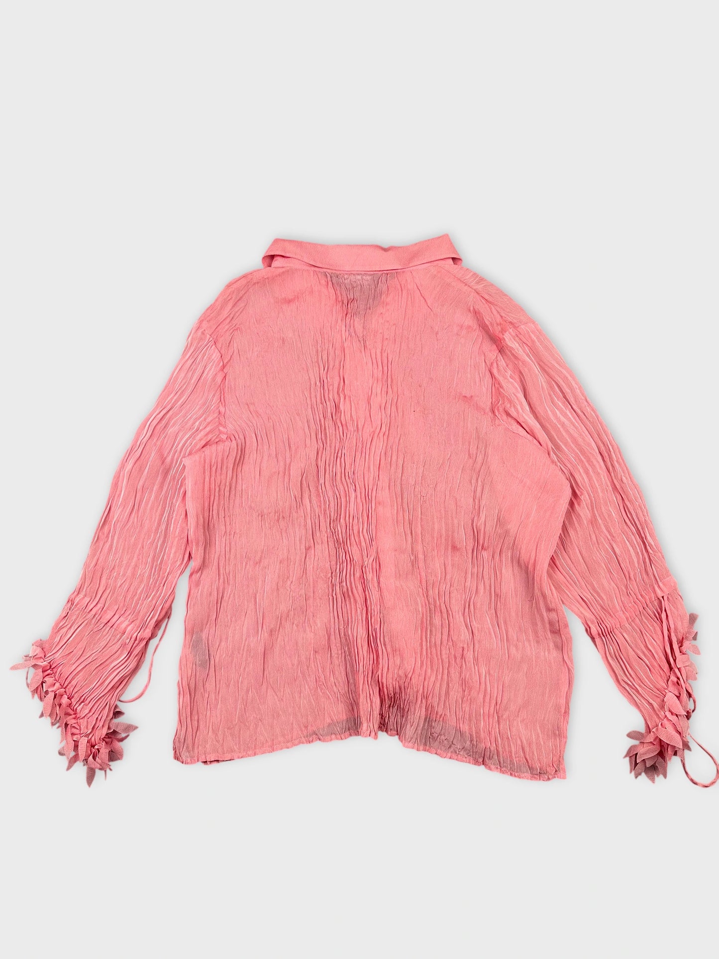 Back view of a long sleeve pink shirt with ruffled cuffs.