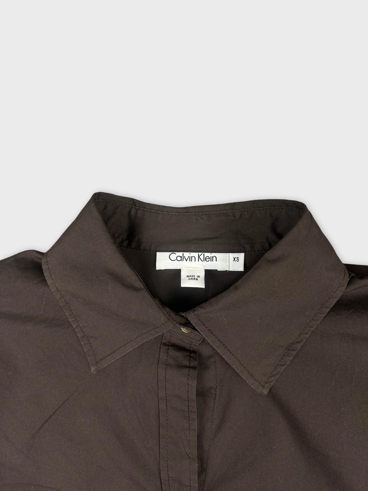 Detail view of a long sleeve shirt in dark brown with a collar.