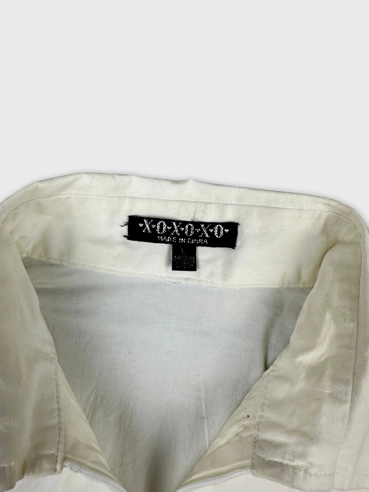 Detail view of a long sleeve shirt in off-white with collar and inner label.