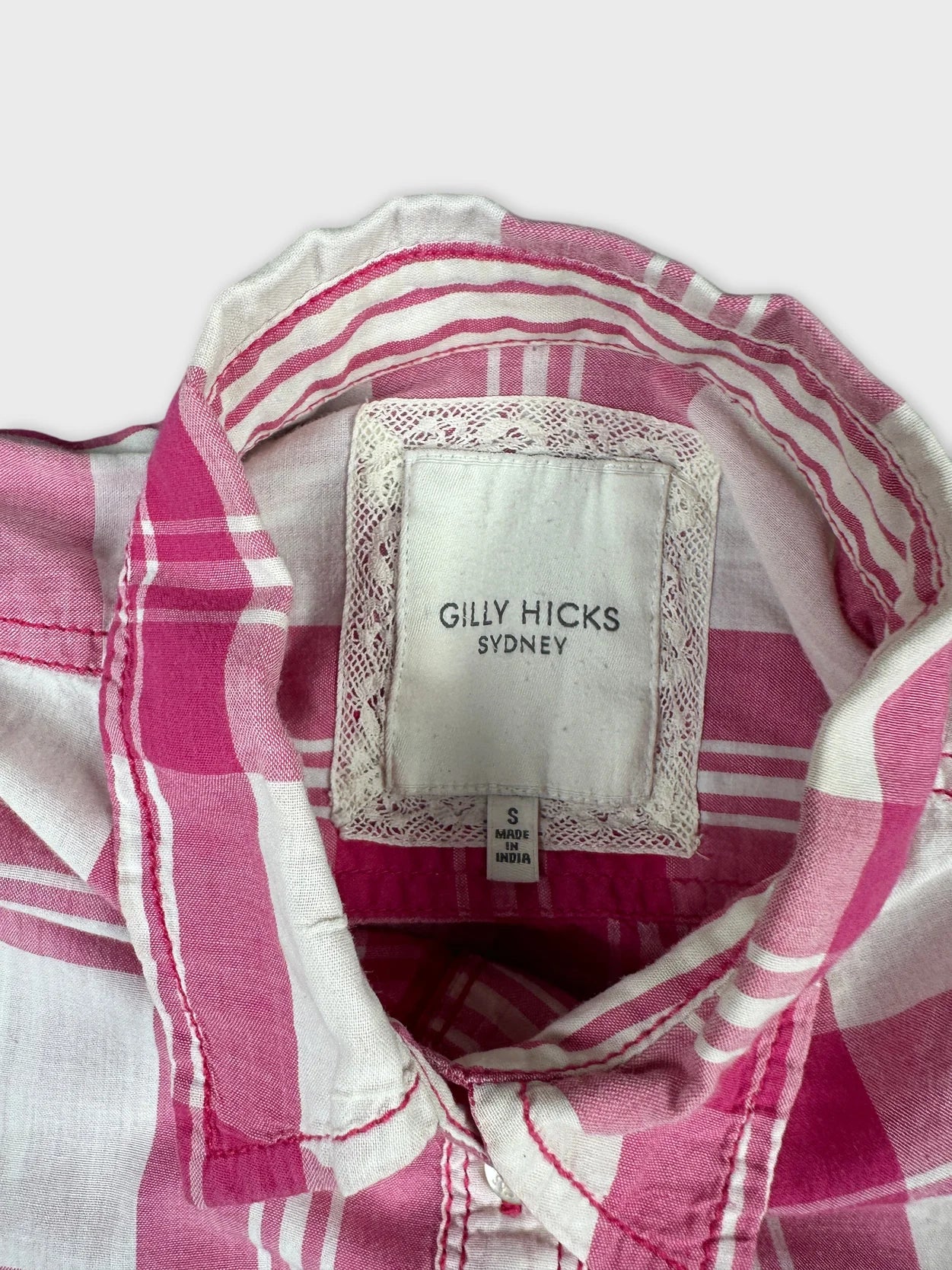 Detail view of a long sleeve shirt in pink plaid with lace trim.