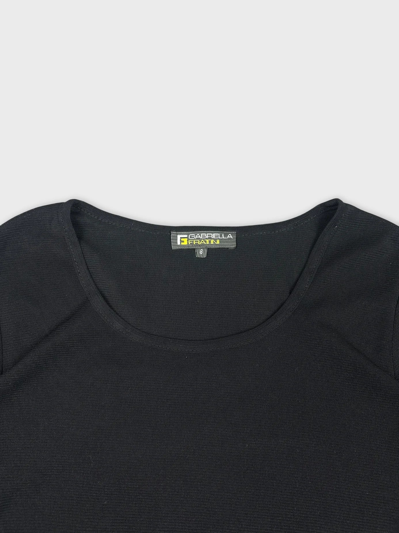 Detail view of a black long sleeve shirt with a scoop neckline.
