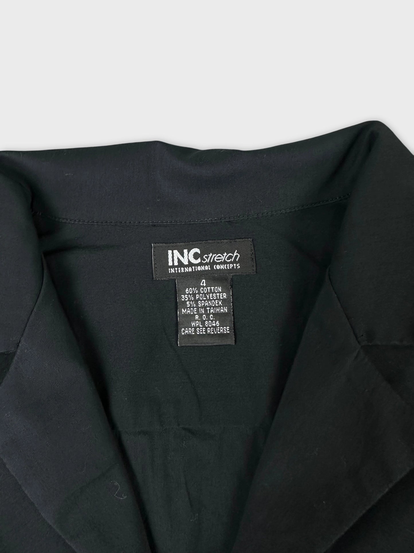 Detail view of a black long sleeve shirt with collar and care tag.