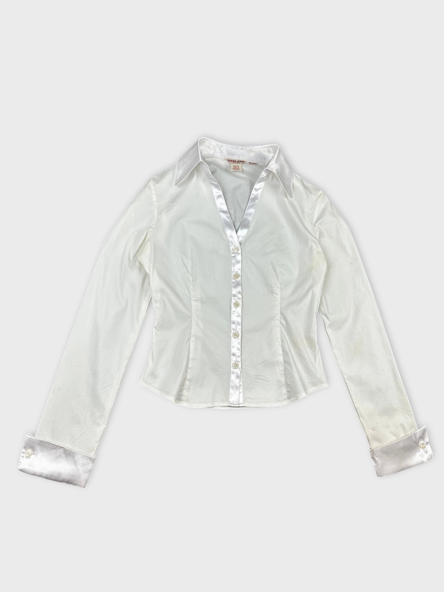 Detail view of a white long sleeve shirt with satin trim.