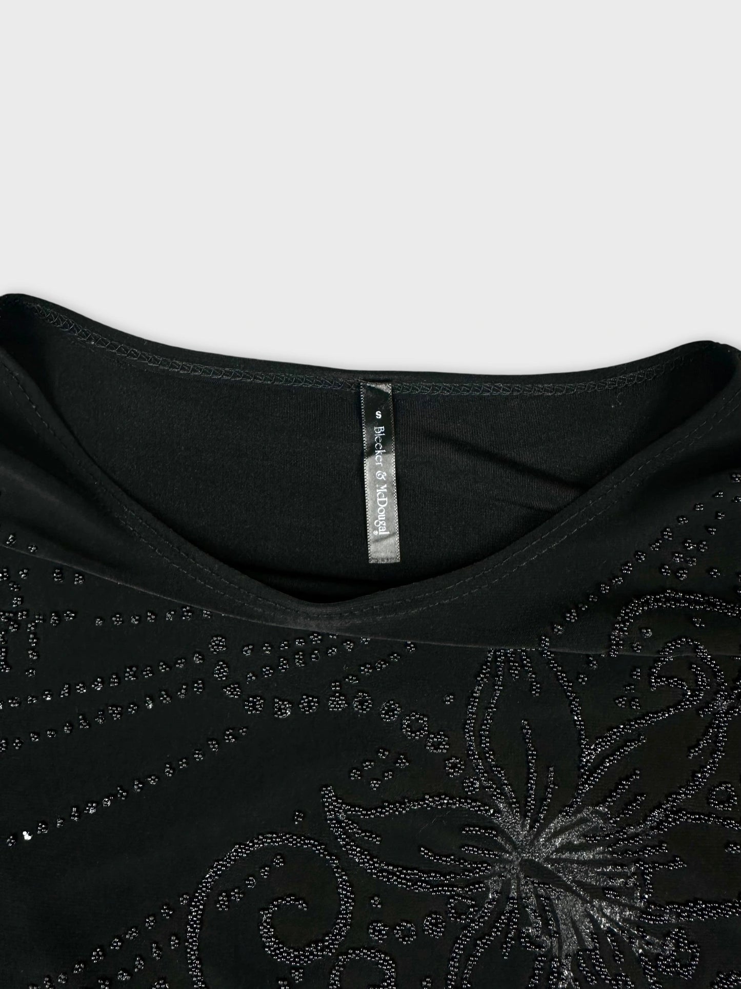 Detail view of black long sleeve shirt featuring sparkly floral patterns.