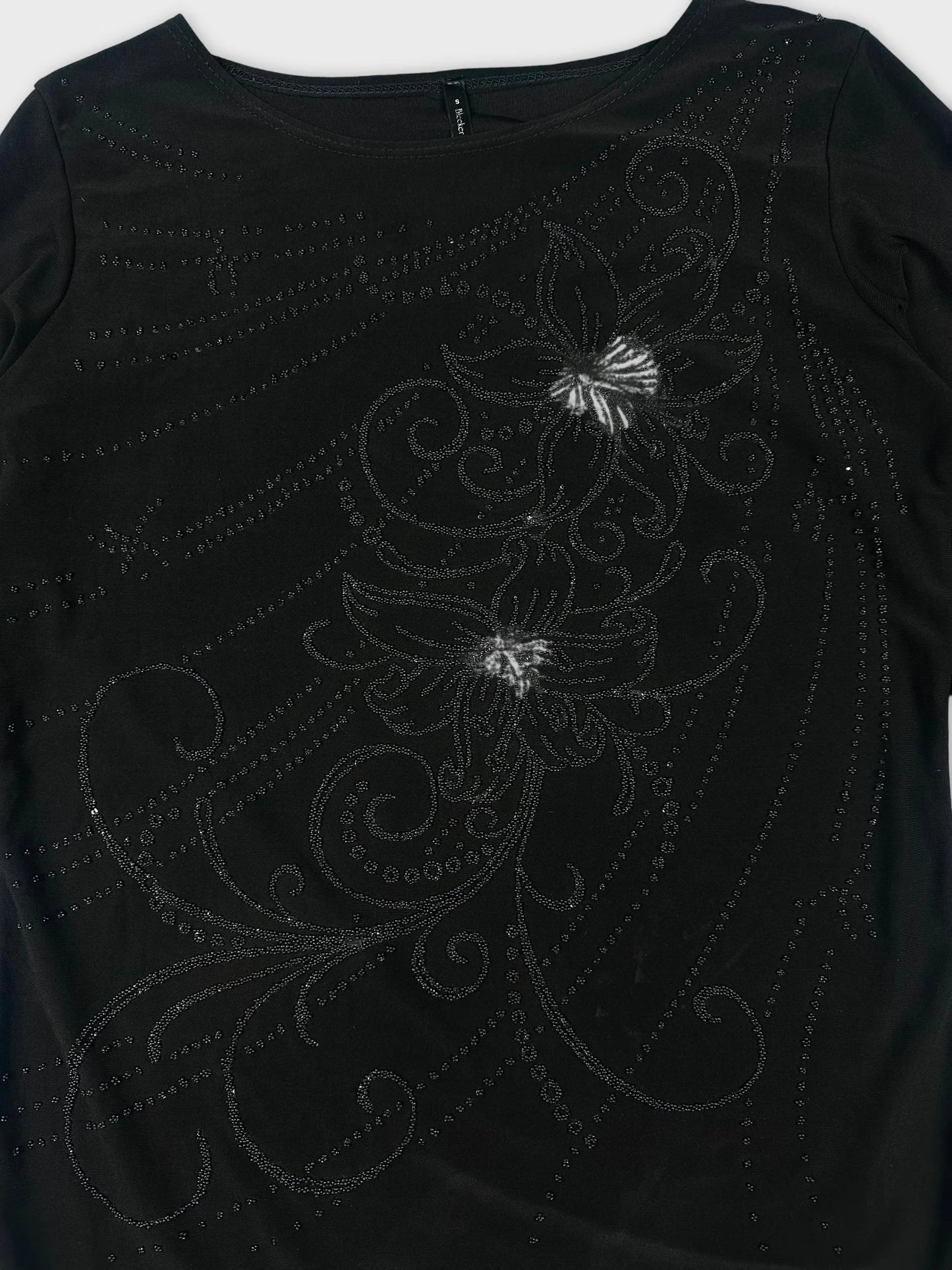 Detail view of a black long sleeve shirt with floral embellishments.