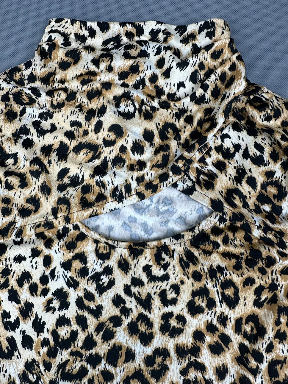 Detail view of a long sleeve shirt in beige with black leopard print.