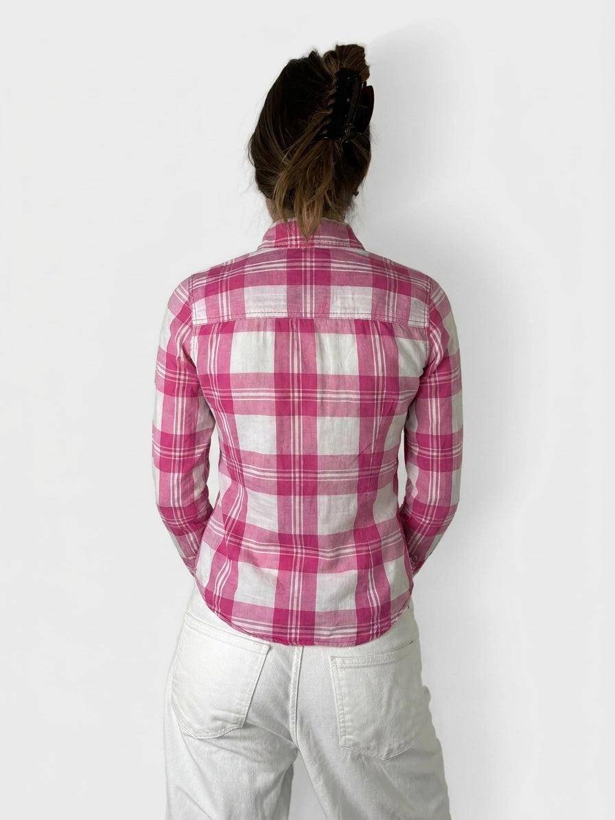 Back view of a pink plaid long sleeve shirt featuring a curved hemline.