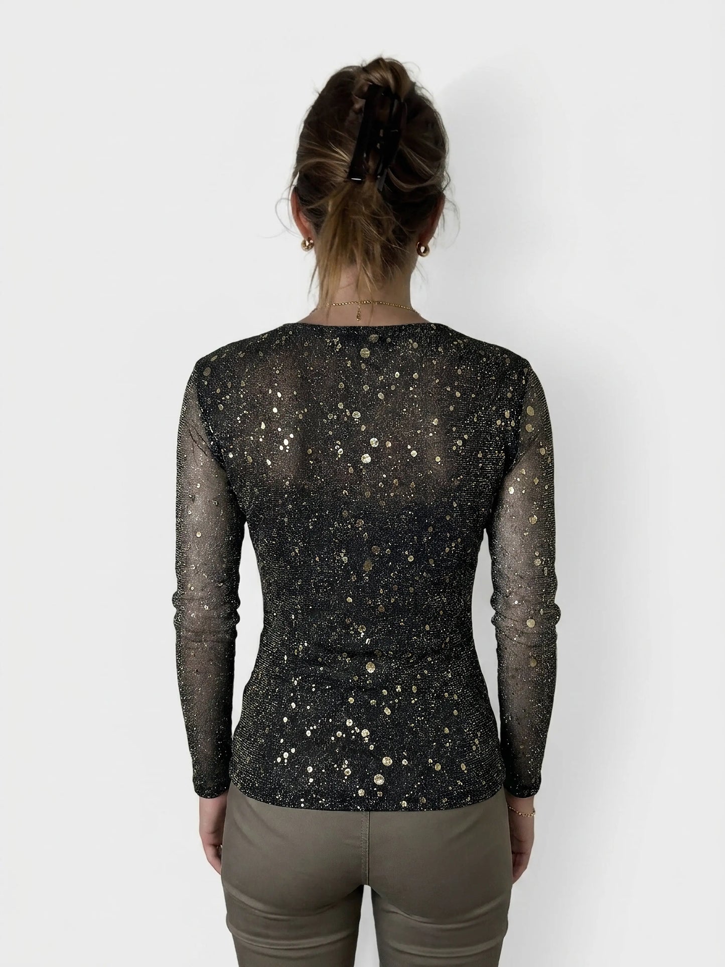 Back view of a black long sleeve top with gold speckled pattern.