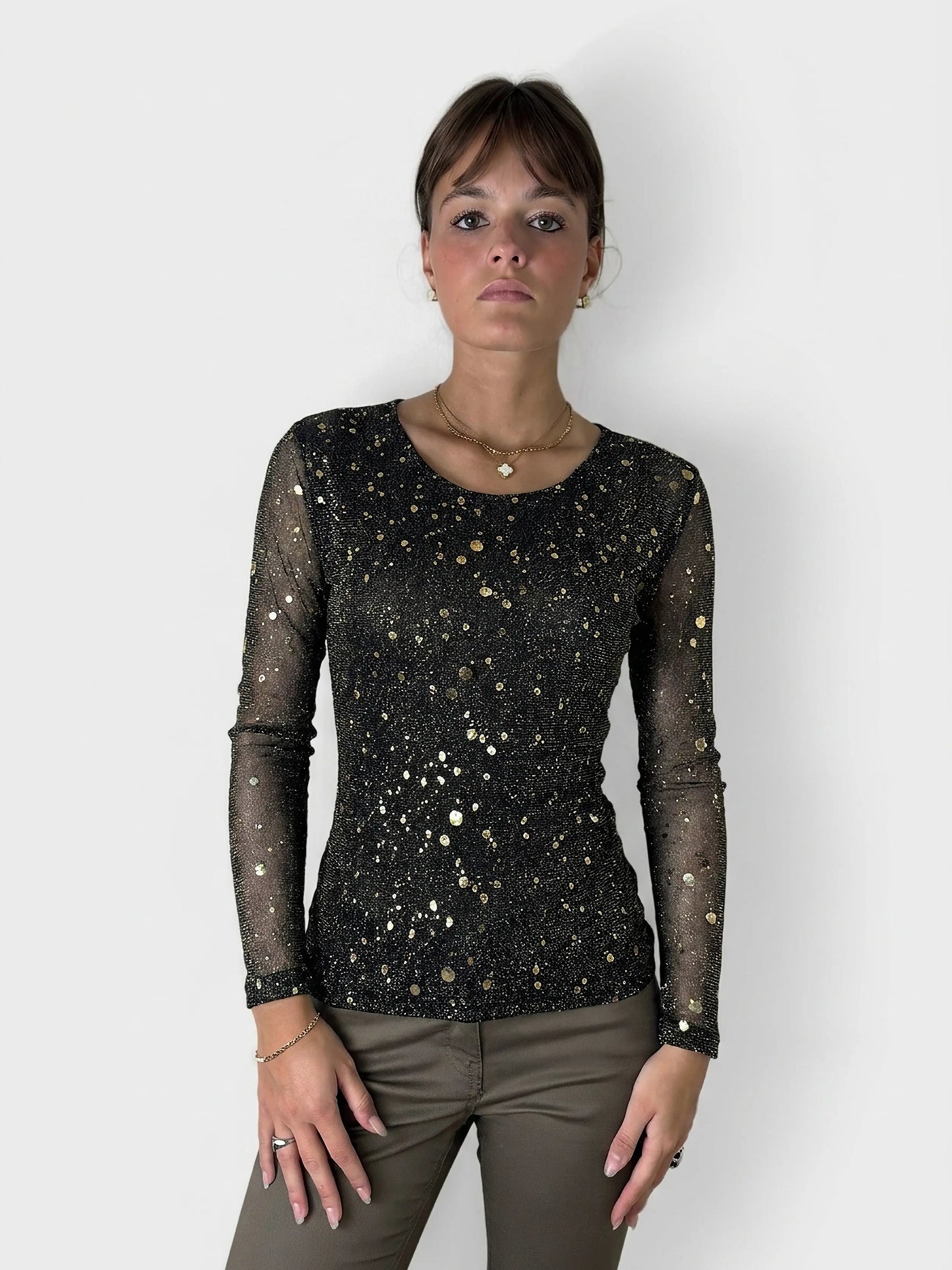 Front view of a black long sleeve top with gold dot pattern.