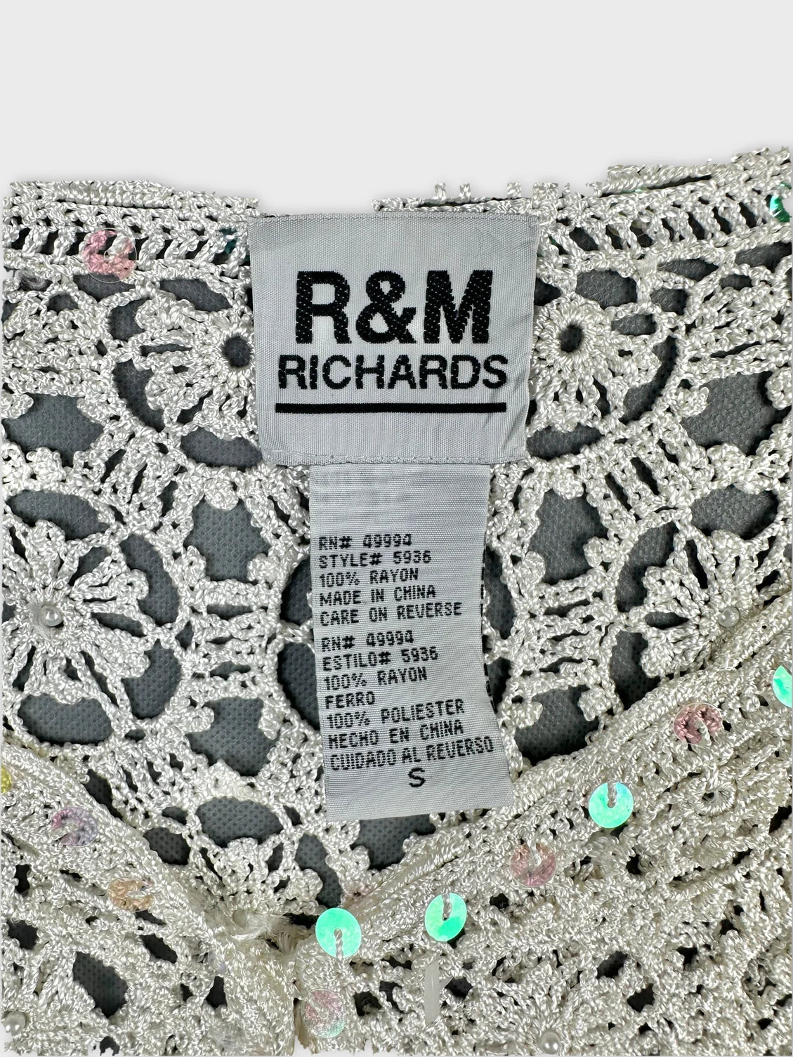 Detail view of a silver long sleeve top with floral lace pattern.