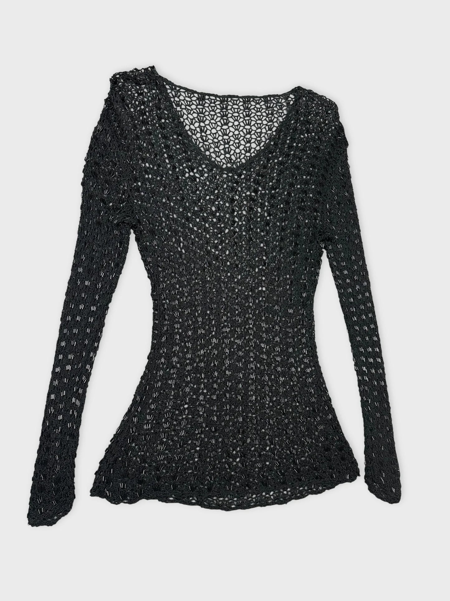 Detail view of a black long sleeve top with a knit pattern.