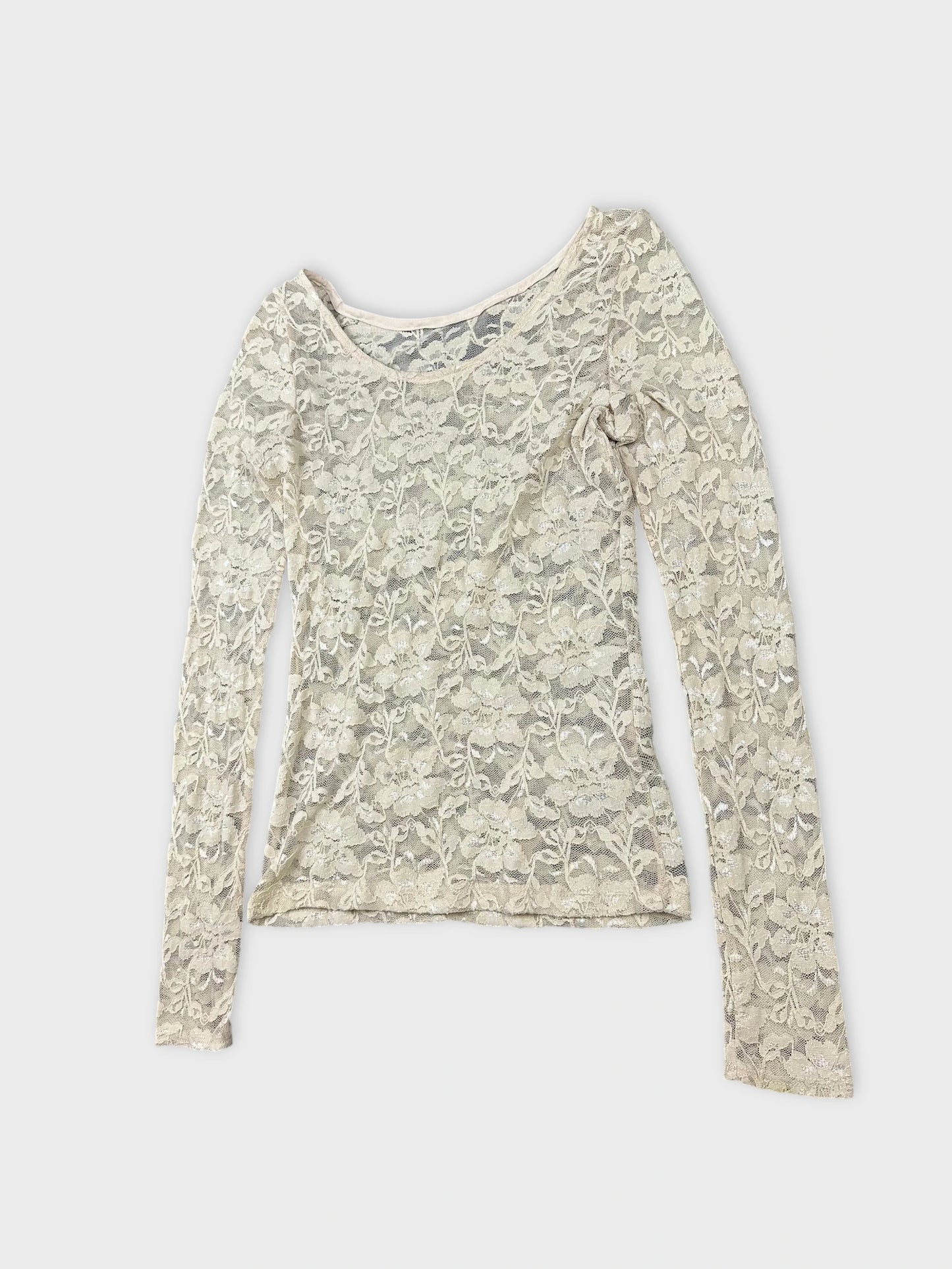 Detail view of a cream long sleeve lace top with floral pattern.