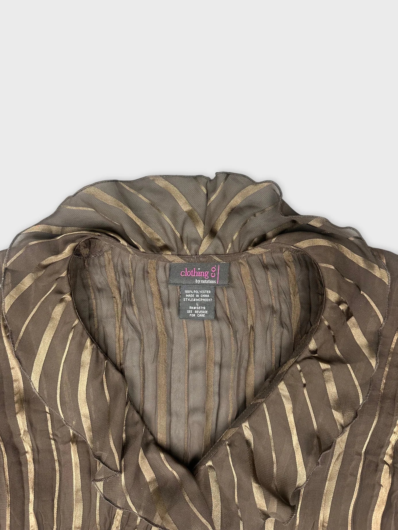 Detail view of a women's long sleeve top in brown with gold striped pattern.