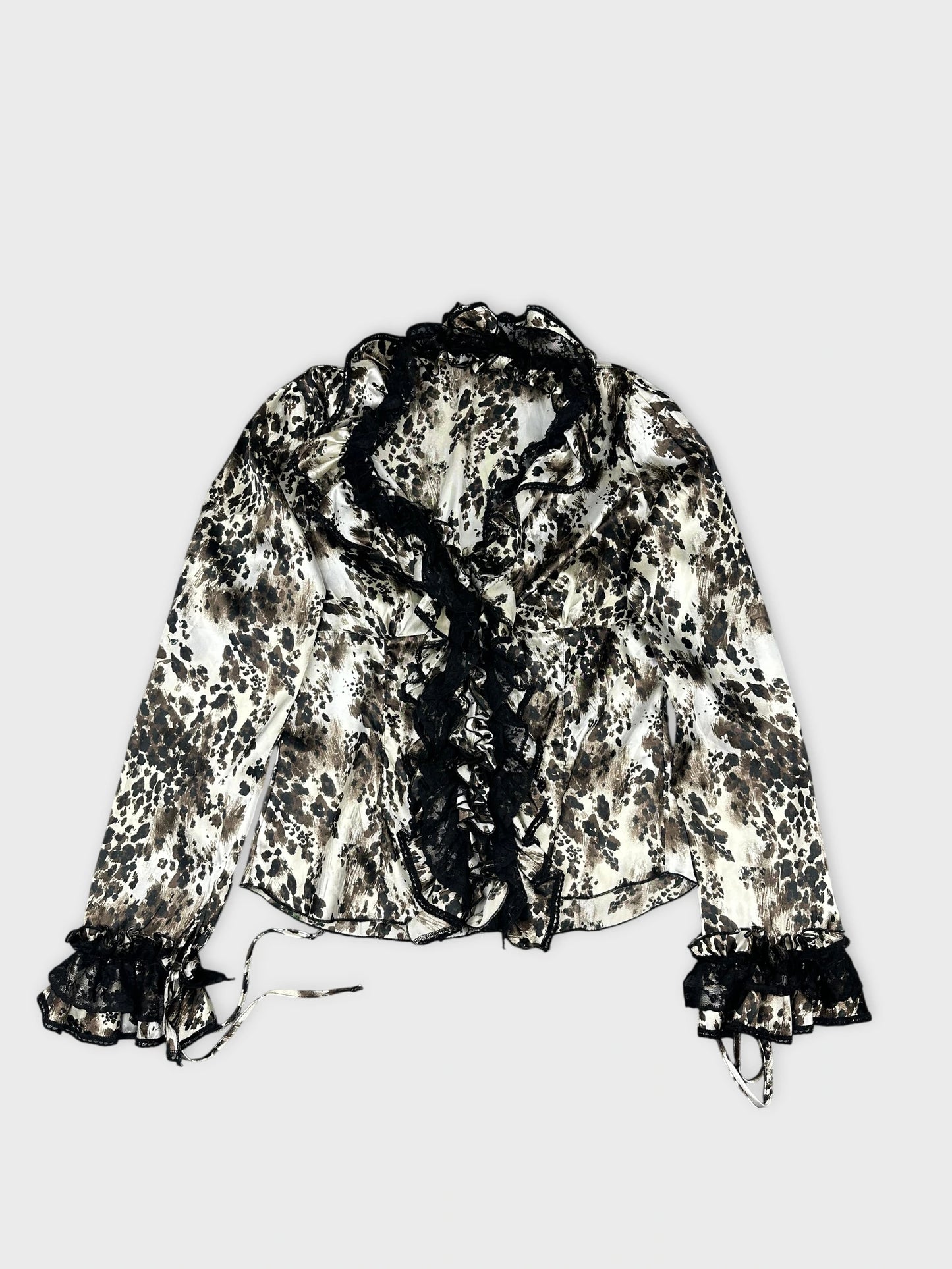 Detail view of a long sleeve top in cream with a black floral pattern.