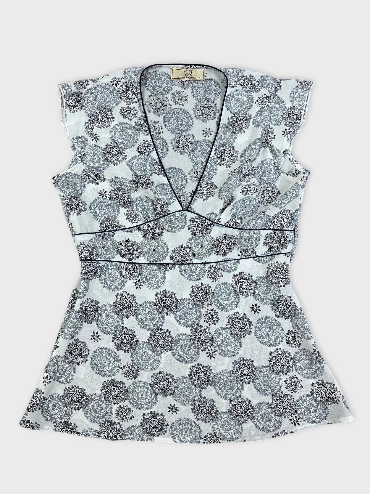 Detail view of a women short sleeve top in light gray with floral print.