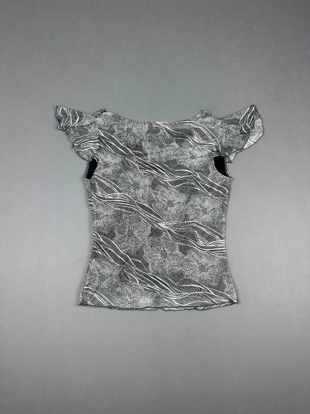 Back view of a short sleeve top in black and white floral pattern.