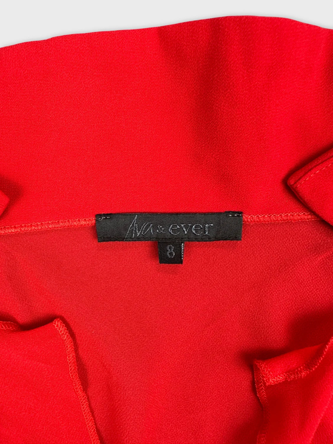 Detail view of red long sleeve top with tag visible.